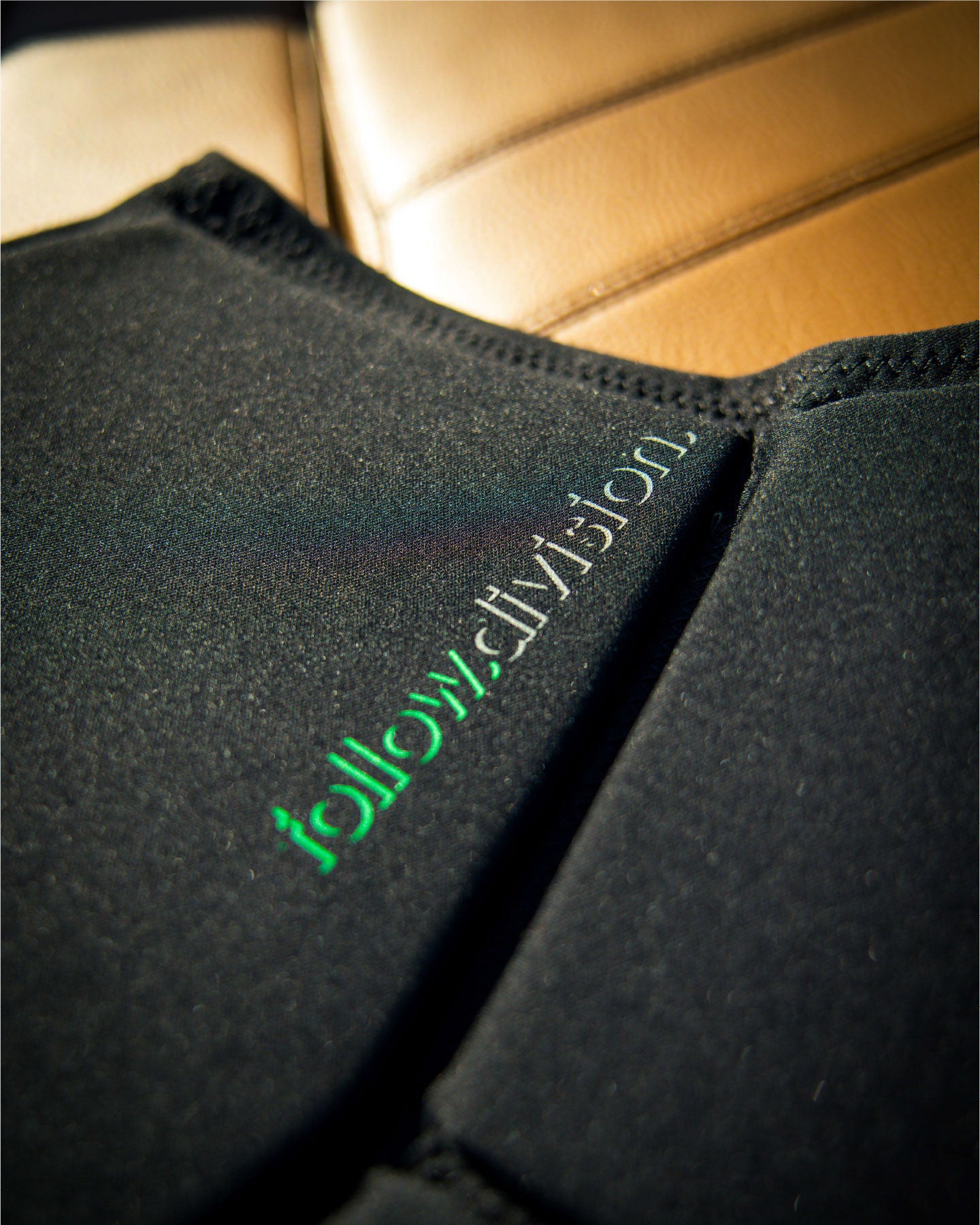 Black fabric with 'follow' logo on a beige leather surface