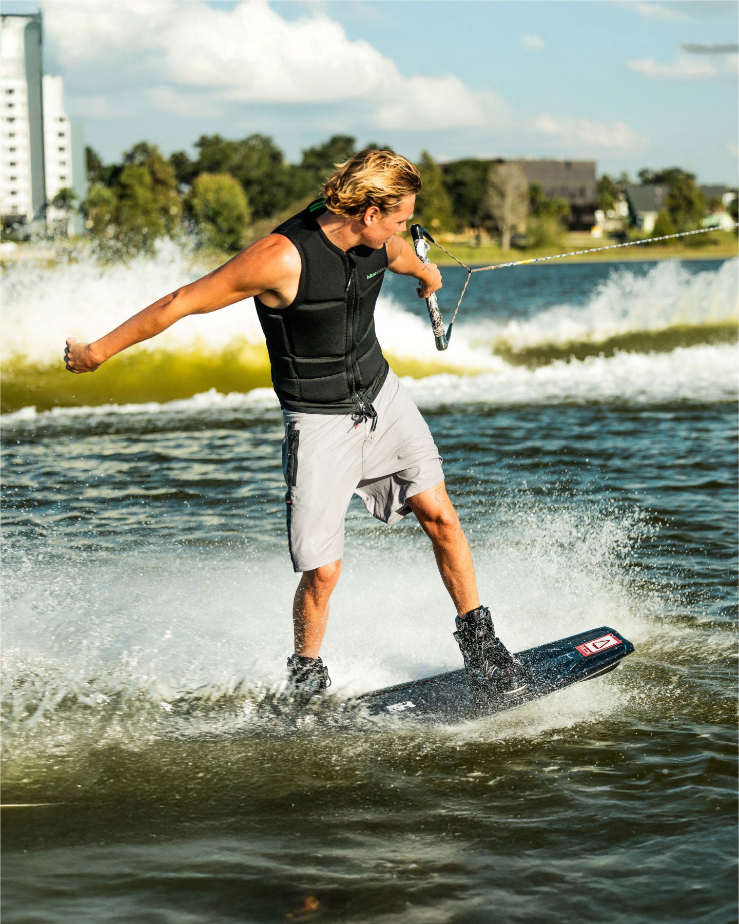 Person wakeboarding on a lake with a cityscape in the background