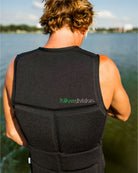 Person wearing a black life vest with 'followdivision' branding by a body of water.