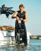 Person preparing to water ski with a wakeboard on a boat in the background
