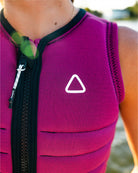 Close-up of a person wearing a pink life jacket with a white follow brand triangle logo, outdoors.