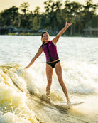 Woman wakeboarding on a lake with trees in the background